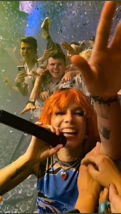 a woman with red hair holding a microphone in front of a group of other people