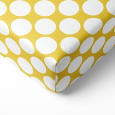 a yellow and white polka dot crib sheet