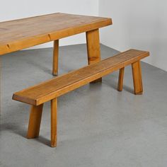 a wooden bench sitting on top of a cement floor next to a white wall,