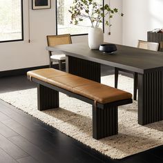 a dining room table with a bench in front of it and a vase on top