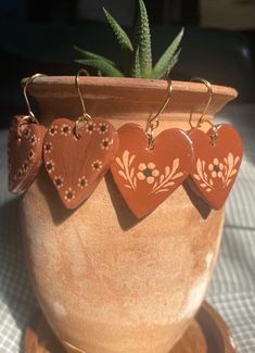 three heart shaped earrings hanging from a potted plant