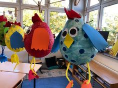 three paper birds hanging from the ceiling in a classroom