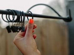 a hand holding an umbrella in front of a wooden fence with wires attached to it