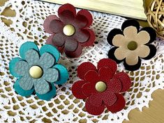 three different colored flowers are on a doily