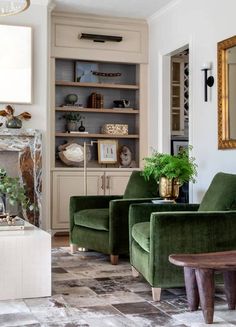 a living room with two green chairs and a fire place in the middle of it