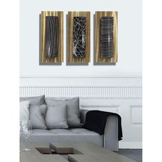 two metal art pieces hanging on the wall above a couch in a white living room