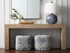 a wooden table topped with two baskets under a mirror