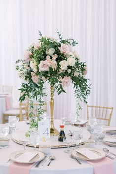 a tall vase with flowers is on top of a white table cloth covered round table