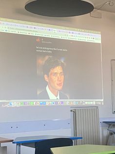 a man is giving a presentation in front of a classroom full of desks and chairs