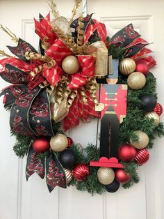 a christmas wreath on the front door decorated with red, gold and black ornaments is hanging