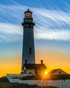 a lighthouse with the sun setting behind it