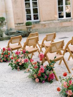 rows of wooden chairs lined up in front of a building with pink and red flowers