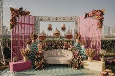 an outdoor wedding setup with flowers and greenery on the ground, in front of a large mirror