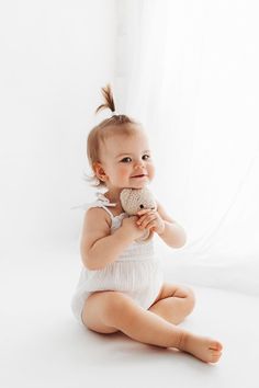 a baby sitting on the floor holding a stuffed animal