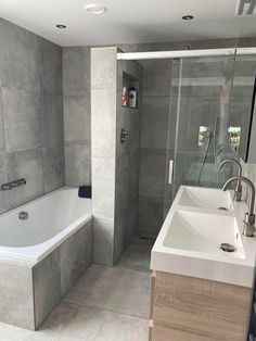 a bathroom that has a sink and a bathtub in it, with a glass shower door