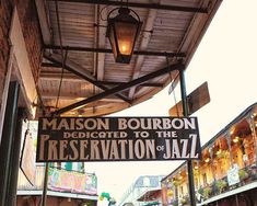 a street sign hanging from the side of a building next to a sidewalk with people walking on it