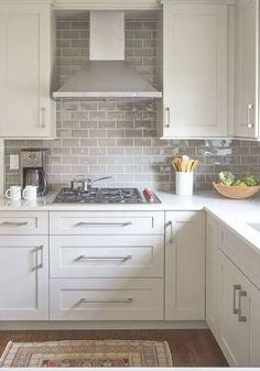 a kitchen with white cabinets and gray tile backsplash