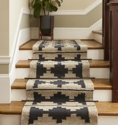 a set of stairs with rugs on them and a potted plant in the corner