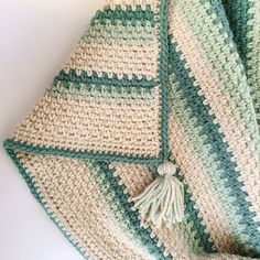 a green and white crocheted blanket laying on top of a table