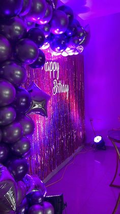 purple and black balloons are hanging from the ceiling in front of a happy birthday sign