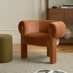 an orange chair sitting on top of a wooden floor next to a green ottoman and white rug