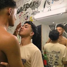 a man shaving his face in front of a mirror with other men standing around