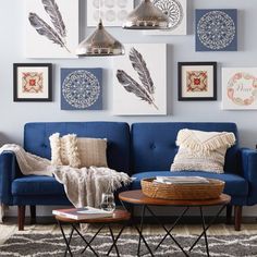 a living room with blue couches and pictures on the wall above them in various frames