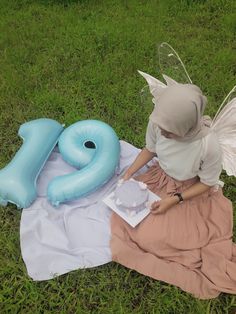 a woman sitting on the ground next to an inflatable number