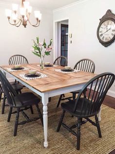 a dining room table with four chairs and a clock on the wall behind it,