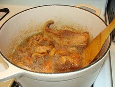 a large pot filled with food on top of a stove next to a wooden spoon