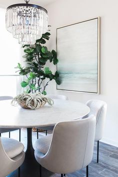 a dining room table with white chairs and a chandelier hanging from the ceiling