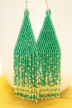 Handmade artisan boho chandelier earrings in the most gorgeous shades of emerald green and gold with gently swaying fringe. Each tiny bead is selected and hand sewn into place, one at a time with a needle and thread. No plastics, no glue, no looms - completely hand stitched with strong nylon thread.Ear wires are gold filled.Lightweight and comfortable, these earrings make a great gift or stocking stuffer for that special woman or a treat for yourself. All our items ship boxed and ready to gift. Traditional Green Beaded Earrings For Party, Traditional Green Beaded Party Earrings, Green Dangling Bead Chandelier Earrings, Green Beaded Bohemian Chandelier Earrings, Green Bohemian Chandelier Earrings With Dangling Beads, Bohemian Green Beaded Chandelier Earrings, Green Beaded Earrings With Dangling Beads For Celebrations, Green Beaded Dangling Earrings For Celebration, Green Dangling Beads Earrings For Celebration