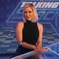 a woman with blonde hair is sitting in front of a glass table and posing for the camera