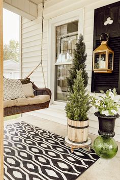 the porch is decorated with potted plants and hanging from chains on the front door