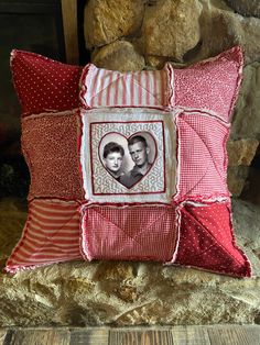 a red and white pillow with a picture of two people in the heart on it