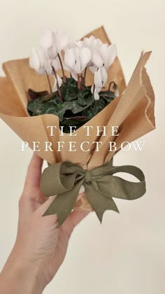 a hand holding a bouquet of flowers with the words let the perfect bow on it