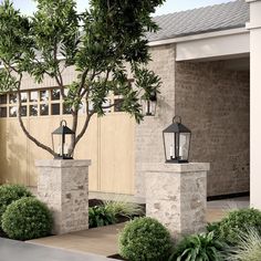 two stone pillars with lanterns on them in front of a brick wall and shrubbery