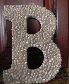 the letter b made out of pearls is sitting on a table next to a door