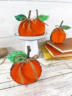 two small pumpkins sitting on top of a table next to books and twine