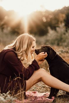 a woman is sitting on the ground with her dog and petting it's face