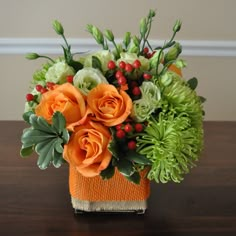 an orange and green flower arrangement on a table