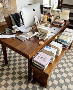 a wooden desk topped with lots of books and a computer monitor on top of it