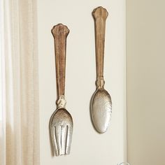 two spoons hanging from the side of a wall