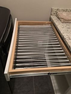 an open drawer in the middle of a kitchen counter top with stainless steel bars on it