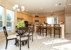 a kitchen and dining room with tile flooring in an open concept home, which is well lit by sunlight coming through the windows