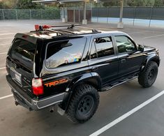 a black truck parked in a parking lot next to an empty parking space with no people