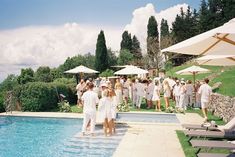 a group of people standing next to a swimming pool