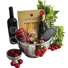 an assortment of food and wine in a colander with tomatoes, parmesan cheese, pasta sauce, basil leaves