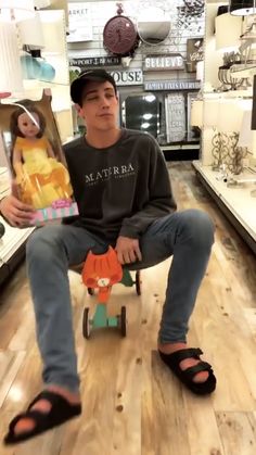 a boy sitting in a store with a toy fox on top of his tricycle