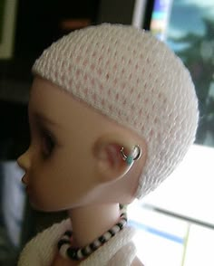 a close up of a doll wearing a white hat with ear rings on it's head